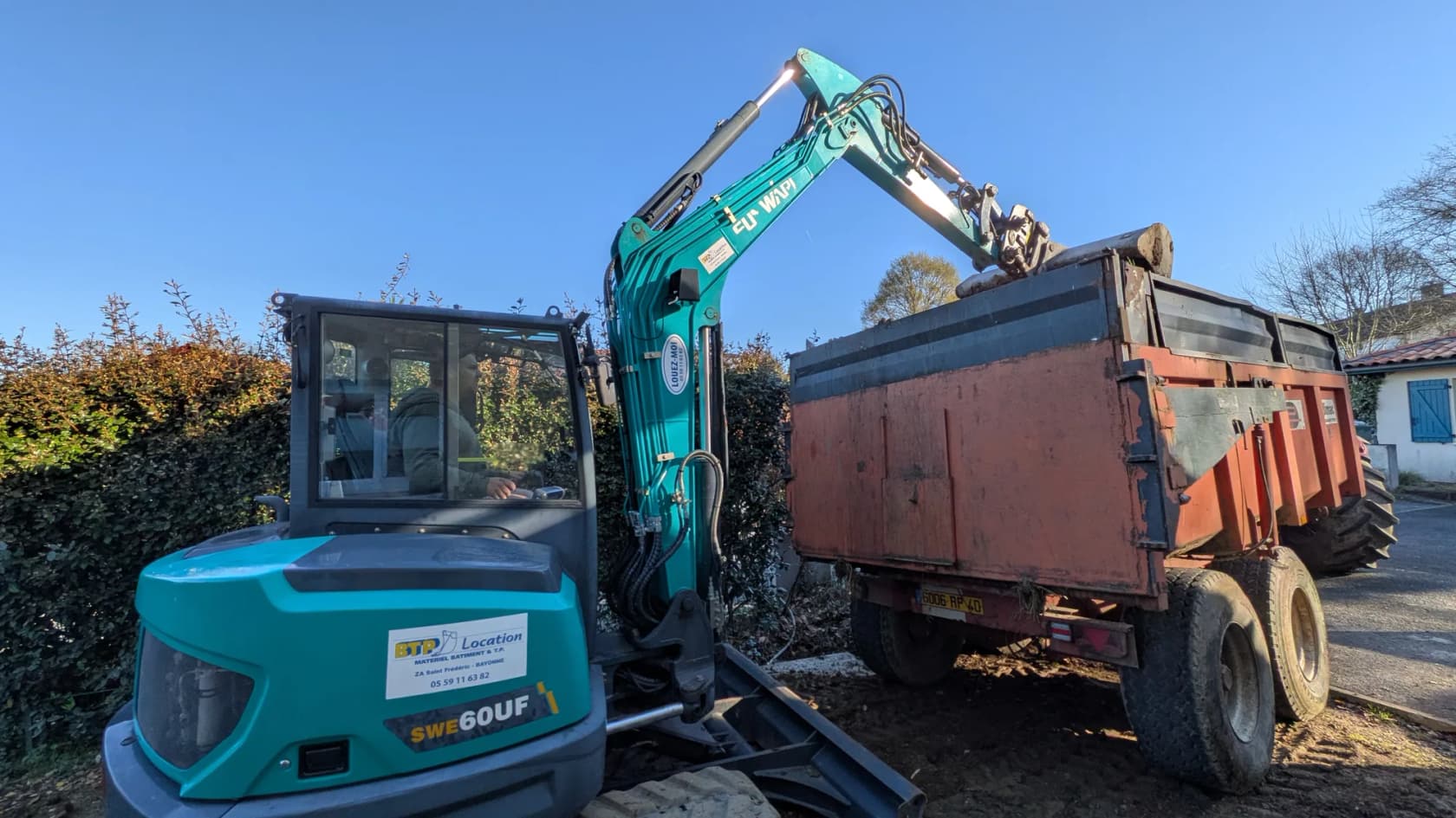 Mini-pelle et camion benne pendant un terrassement de piscine